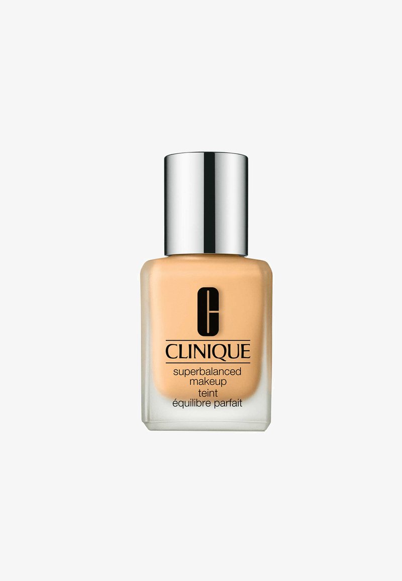 Base de maquillaje Clinique Superbalanced en un frasco de vidrio, color beige, con una tapa de rosca plateada y un logo negro en la parte frontal.