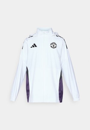 Veste blanche zippée avec des panneaux latéraux noirs et violets. Équipée du logo Adidas et du blason de Manchester United sur la poitrine. Matériau léger.