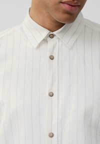 Lichtgekleurde gestreepte shirt met een button-down kraag, voorzien van houten knopen en een gestructureerde stof. Fijne verticale strepen zichtbaar.