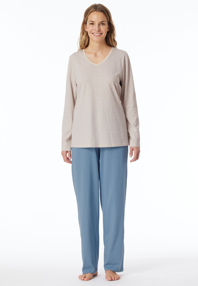 Langärmeliger Schlafanzugoberteil in hellem Beige mit einem geometrischen Muster, kombiniert mit lockeren, hellblauen Hosen aus weichem, leichtem Stoff.