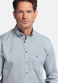 Overhemd met knopen in een blauw-wit geometrisch patroon. Bevat een spread collar en lange mouwen met knoopmanchetten.
