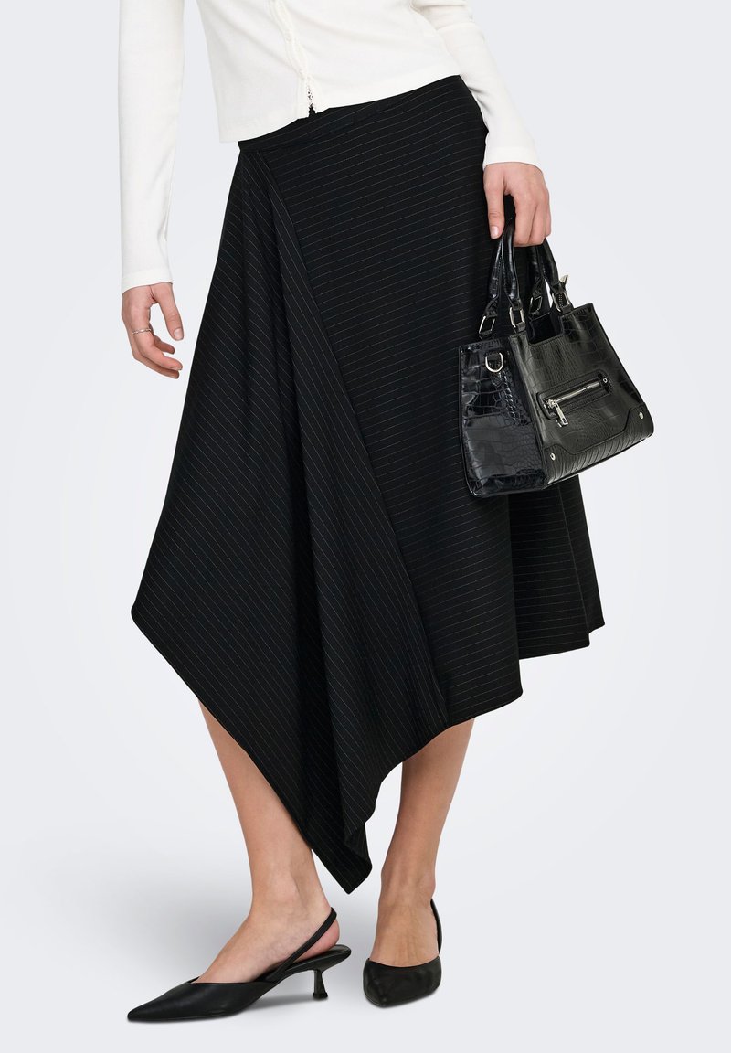 Jupe noire asymétrique avec des rayures verticales subtiles, associée à un sac à main texturé noir et à des chaussures pointues noires. Texture de tissu lisse.