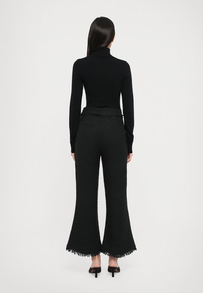 Black turtleneck top and high-waisted, black, textured flared pants with fringed hems, featuring a smooth finish and minimal detailing.