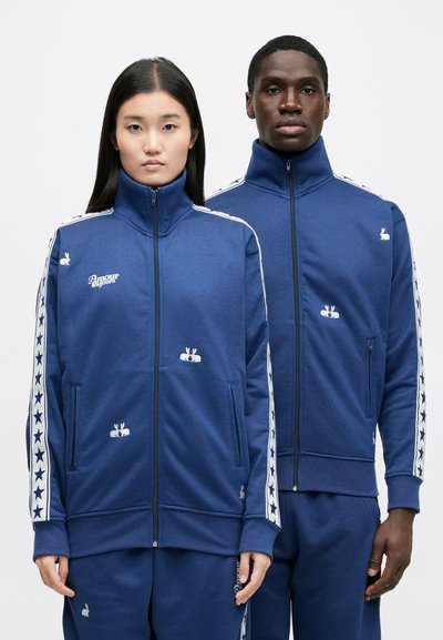 Mörkblå zip-up-jackor i mjukt tyg med hög krage, stjärnmönstrade sidostripes och broderade kanindekorer på framsidan.