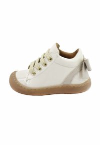 Zapato de charol blanco con punta redonda, ojetes dorados, cordones de beige texturizado y suela de goma beige; presenta un pequeño lazo en el talón.