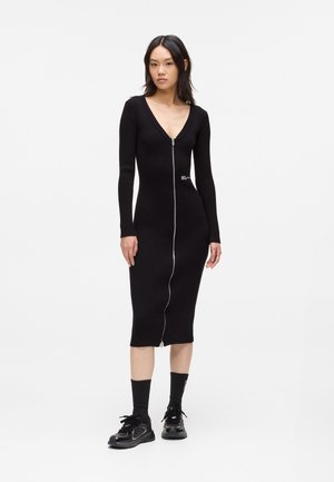 Black ribbed midi dress with long sleeves and a deep V-neckline, featuring a central zipper and small logo detail on the side.