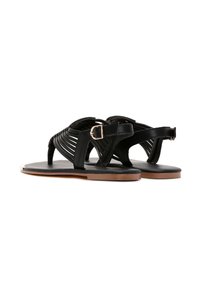 Black leather sandals feature woven straps, a buckle closure, and a flat sole with a slight tan accent, emphasizing a minimalist design.