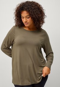 Maglia a manica lunga verde oliva in tessuto morbido, con scollo rotondo e vestibilità rilassata, con dettagli leggermente arricciati ai lati.