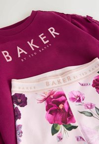 Burgundský svetr s nápisem "BAKER" ve světle růžové barvě, spolu se světle růžovými legínami s květinovým vzorem a odpovídajícím štítkem na pásu.