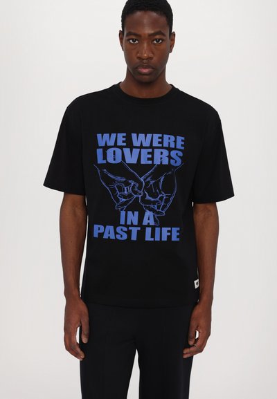 Schwarzes T-Shirt mit kurzen Ärmeln, das blaue Grafiken und eine Illustration von Händen zeigt. Es besteht aus Baumwolle, hat eine lockere Passform und einen Rundhalsausschnitt.