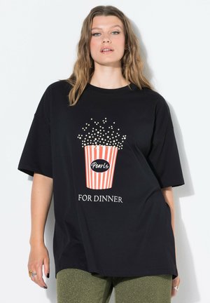 Camiseta negra de gran tamaño con un gráfico de un cubo de palomitas de maíz en rayas rojas y blancas con el texto "Perlas PARA CENAR" en blanco.
