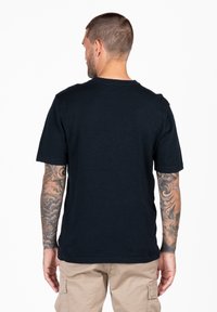 Czarny bawełniany t-shirt z okrągłym dekoltem i krótkimi rękawami, o gładkiej fakturze. Widok z tyłu nie zawiera żadnych grafik ani ozdób.