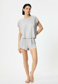 Grå sæt med korte ærmer i pyjamas, med prikker og elastisk talje. Toppen har en løs pasform, og shortsene er knælange.