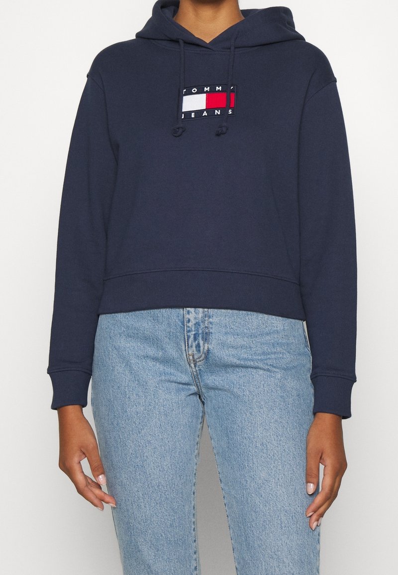 Marinblå kort hoodie i bomull med en framsideslogo i rött, vitt och blått. Långa ärmar med ribs knitted muddar.