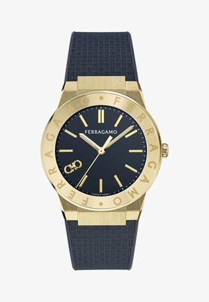 Aranyszínű Ferragamo karóra fekete texturált szíjjal, fekete számlappal, arany színű óraszámozással, mutatókkal és logóval, amelyen egy kis végtelen jel is látható.