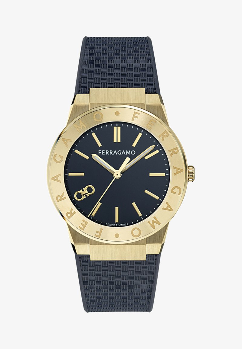 Zelta toņa Ferragamo pulkstenis ar melnu fakturētu siksniņu, melnu ciparnīcu, zelta stundu rādītājiem, rokām un logotipu, ar mazā bezgalības simbola detaļu.