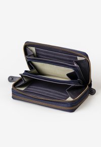 Marine blauwe zip-around portemonnee met leren buitenkant en binnenvakjes voor kaarten, gecombineerd met een groene gestreepte textile voering en gouden ritsdetails.