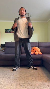 Uformell antrekk med en hvit t-skjorte, olivengrønn jakke, mørke jeans og svart-hvite joggesko. En myk oransje blekksprut i bakgrunnen.