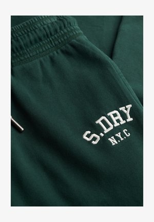Pantalon de survêtement vert avec une taille élastique et un texte brodé blanc "S.DRY N.Y.C." sur la cuisse. Texture lisse et douce.