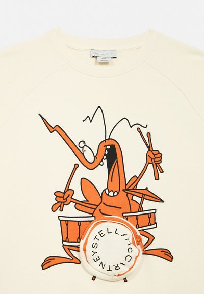 Tegneserieagtig orange hummer, der spiller trommer på cremefarvet stof, med tilknyttet rund pung med Stella McCartney-logo på basstrommen.