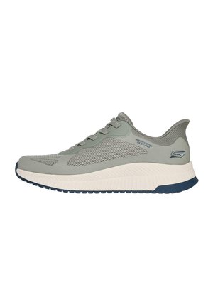 Zapatilla deportiva gris claro con parte superior de malla texturizada, cierre de cordones y una suela blanca y marina en contraste. Presenta un sutil logotipo en el lateral.