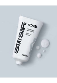 Hvid klemmetube med flad hætte, med sort tekst der står "STAY SAFE" og "Light Day and Night Fluid." Dråber af væske i nærheden.