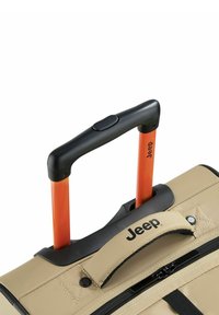 Borsa su ruote beige con manico in plastica nera e due pali di supporto in metallo arancione, con zip e dettagli cuciti, contrassegnata con "Jeep."