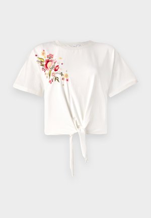 Camiseta blanca de manga corta con un nudo en la parte delantera. Presenta bordados florales en rosa y amarillo en el lado izquierdo. Material de algodón suave.