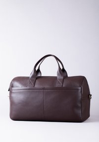 Brown leather duffel bag with two rounded handles, a rectangular shape, and a textured surface. Features a front pocket and gold hardware.