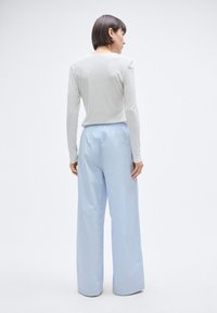 Ανοιχτό γκρι μακρυμάνικη  μπλούζα συνδυασμένη με ανοιχτό μπλε φαρδιά παντελόνια· τα παντελόνια διαθέτουν ελαστική μέση και ομαλή, γυαλιστερή υφή.