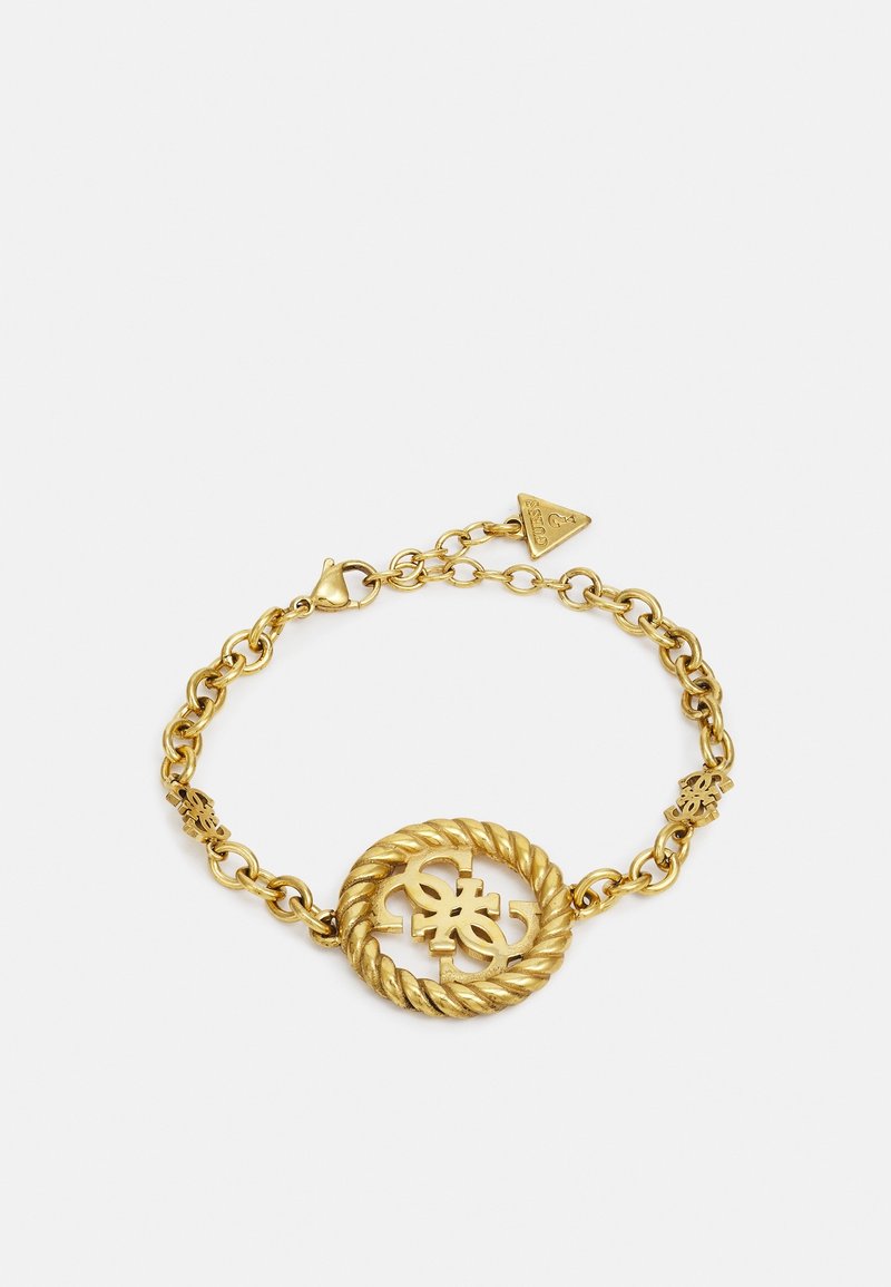 Bracelet chaîne en or avec un élément central circulaire torsadé présentant des lettres entrelacées et une petite étiquette de marque triangulaire près du fermoir.