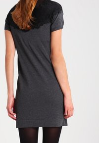 Abito grigio a maglia con maniche corte e spalla decorata in pizzo. Texture liscia con taglio dritto e leggero elastico.