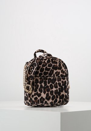 Petit sac à dos imprimé léopard avec une poignée supérieure, une poche avant et des détails de chaîne et boucle dorés sur une surface blanche.
