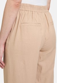 Beige, strukturierte, gewebte Hose mit elastischem Bund und zwei Gesäßtaschen. Der Schnitt ist locker mit einem geraden Bein design.