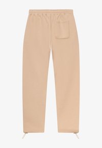 Beige joggebukser med elastisk midje, baklomme og glidelåser ved ankelene. Laget av myk, teksturert stoff.