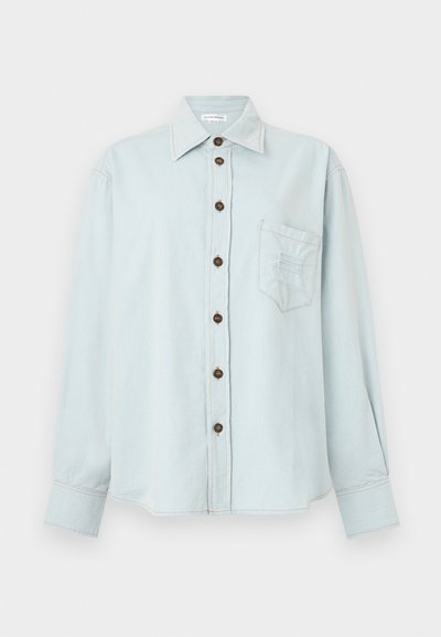 Hele sinine denimsärk, millel on pikad varrukad, nööbid, rinnakott ja õrnalt lõdvestatud istuvus. Särk sisaldab kontrastset õmblemist ja pruune nööpe.