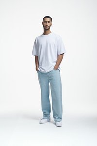 T-shirt blanche oversize, jean bleu clair ample et baskets blanches. Tissu lisse et design simple sur un fond uni.