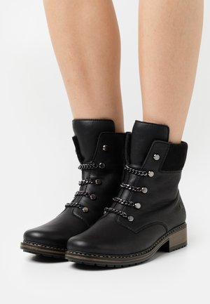 Bottines noires en cuir, avec un design à lacets agrémenté d'accents métalliques, des côtés texturés et un talon épais et à motifs.