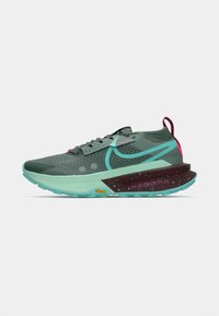 Szürke és teal színű alacsony sportcipő, lila pödörrel a talpán, türkiz Nike logóval és Vibram logóval a talpán.