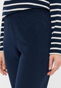 Donkerblauwe sweatpants van zachte fleece met een elastische tailleband, gecombineerd met een gestreept langetermijn T-shirt in navy en wit.