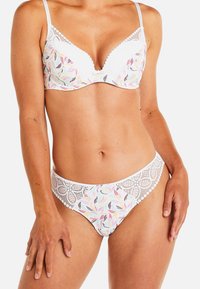 Ensemble de lingerie blanche en dentelle avec un motif floral dans des couleurs pastel. Le soutien-gorge a un décolleté plongeant et des bretelles réglables.