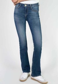 Vervaagde blauwe denim jeans met een rechte snit, vijf zakken, gouden knoopdetails en subtiele stikdetails. Gestyled met witte sneakers.