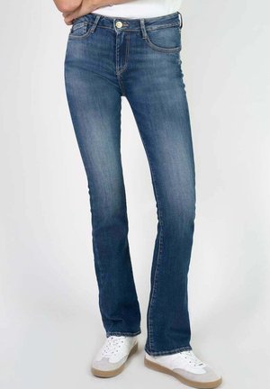 Faded blue denim jeans with a straight-leg cut, five pockets, gold button hardware, and subtle stitching details. Styled with white sneakers.