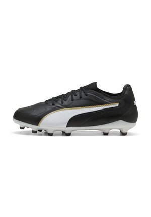 Chaussure de football noir et blanc avec garniture dorée, crampons moulés, col bas et lacets, conçue pour jouer sur terrain ferme.