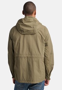 Chaqueta con capucha color verde oliva, de textura ligera y arrugada, con un corte relajado y costuras visibles.
