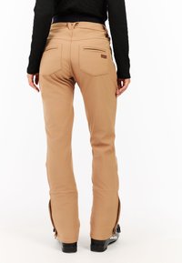 Beige sneeuwbroeken met een slim fit, voorzien van twee achterzakken, een ritsluiting bij de enkels en een gestructureerde stof voor warmte en flexibiliteit.