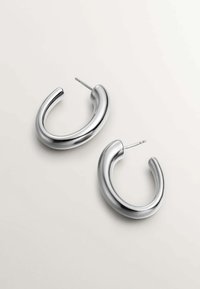 Pendientes de aro plateados con un diseño suave y redondeado. Fabricados en metal brillante, presentan una ligera curvatura y un cierre de tipo post-back.