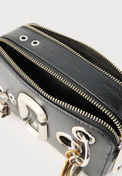 Μαύρη δερμάτινη τσάντα Marc Jacobs με διπλά ασημένια φερμουάρ, ασημένια μεταλλικά στοιχεία και μπρελόκ προσαρτημένο σε ένα μεταλλικό κρίκο.