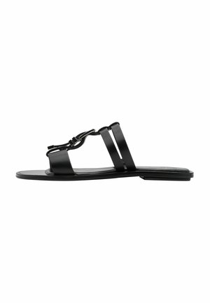 Sort sandal med flad sål, der har to brede remme og en dekorativ kædedetalje. Elegant materiale og minimalistisk design.