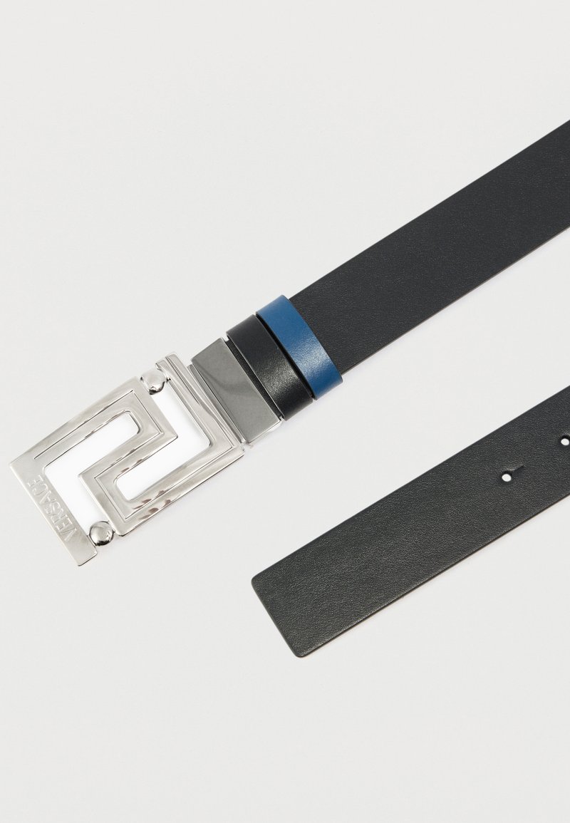 Ceinture en cuir noir avec une boucle géométrique argentée ornée d'un logo embossé. Comprend une sangle accentuée bleu et noir. Texture lisse sur toute la surface.